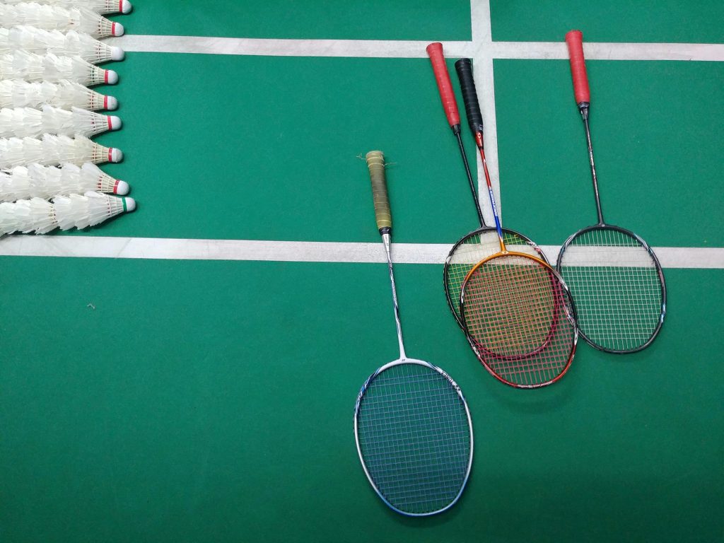 Top view of badminton rackets and shuttlecocks on an indoor court.